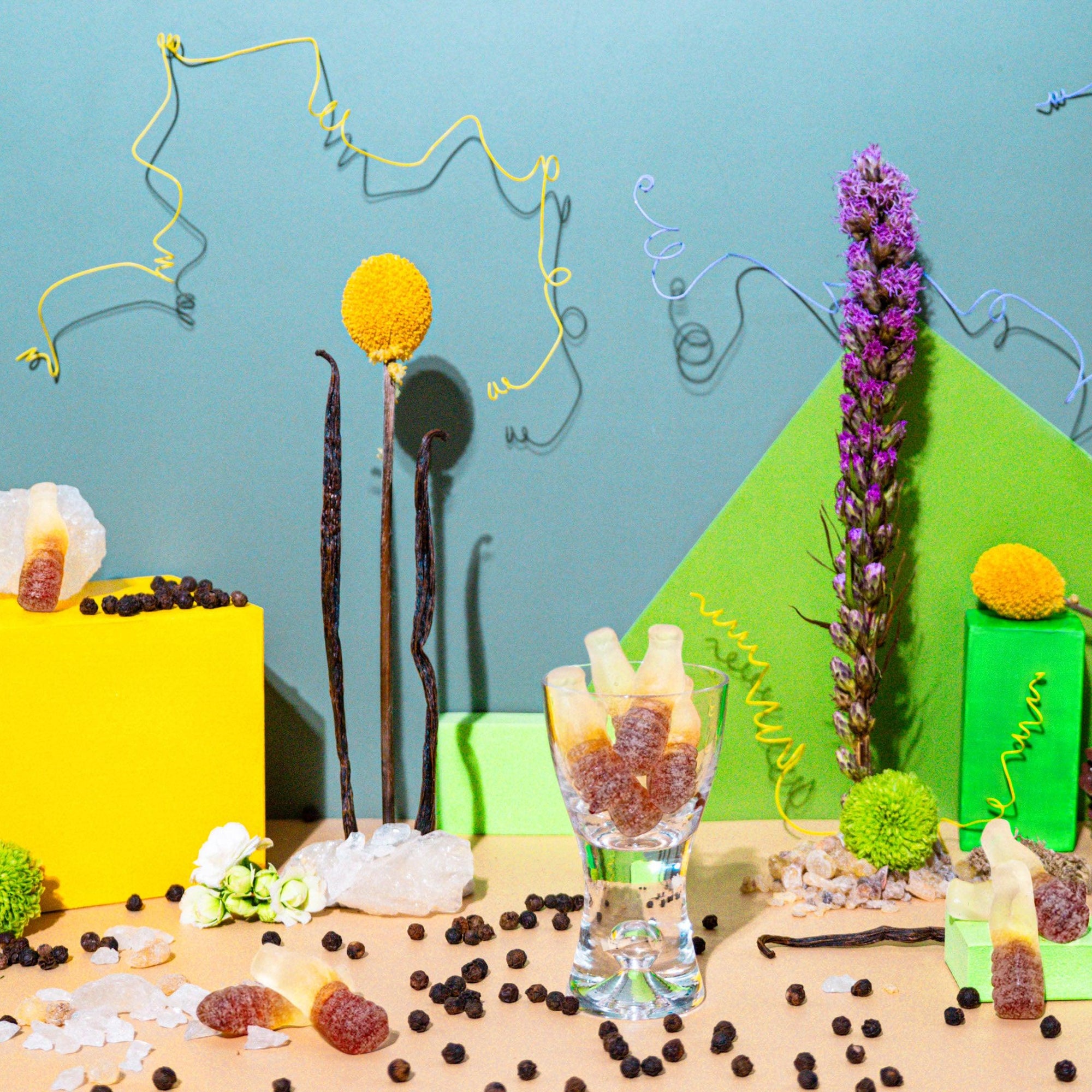 An assortment of objects related to fragrance oil display, including bottles, decorative stones, and plant leaves against a colorful background.