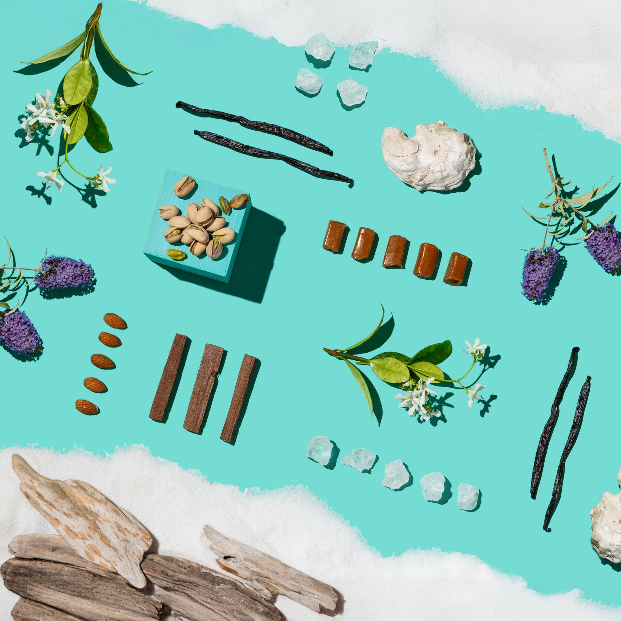 Spices, herbs, and crystals arranged on a turquoise background with white sand.