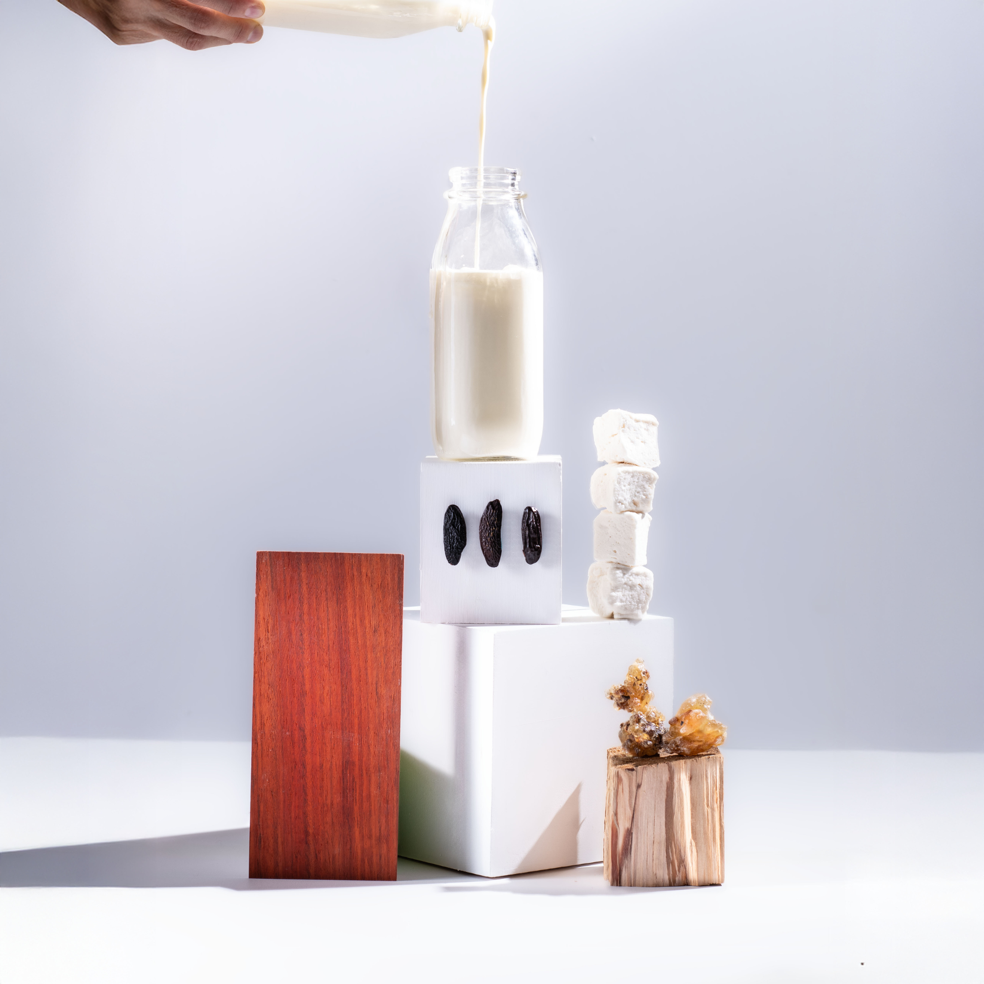 Person pouring liquid into a glass bottle with decorative elements on a light gray background