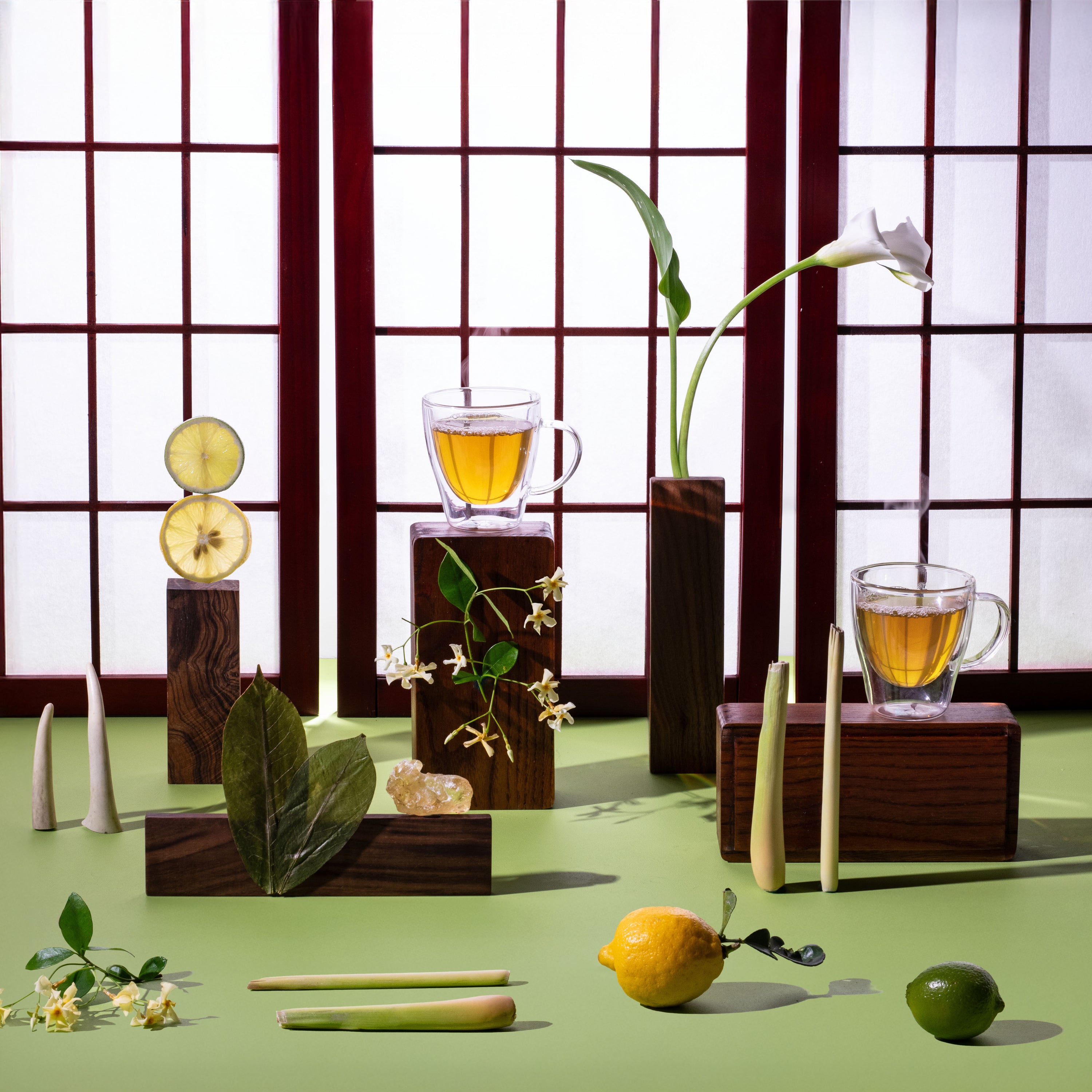 Tea cups with lemon slices on a green surface with a window pane background