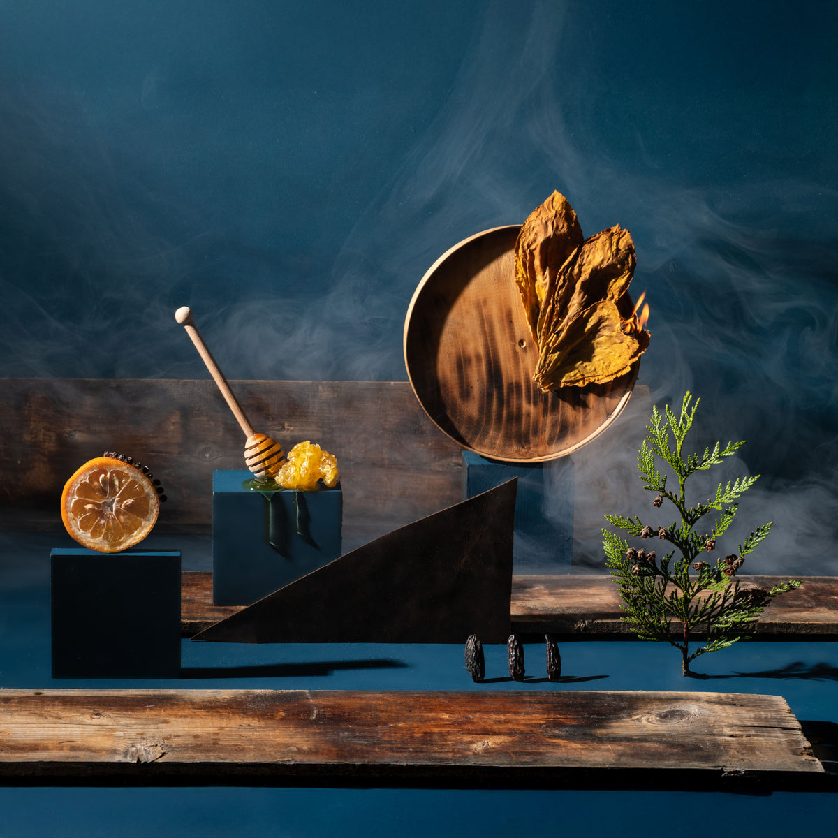 Decorative setup with a wooden wheelbarrow, honey dipper, and dried leaves on a dark background