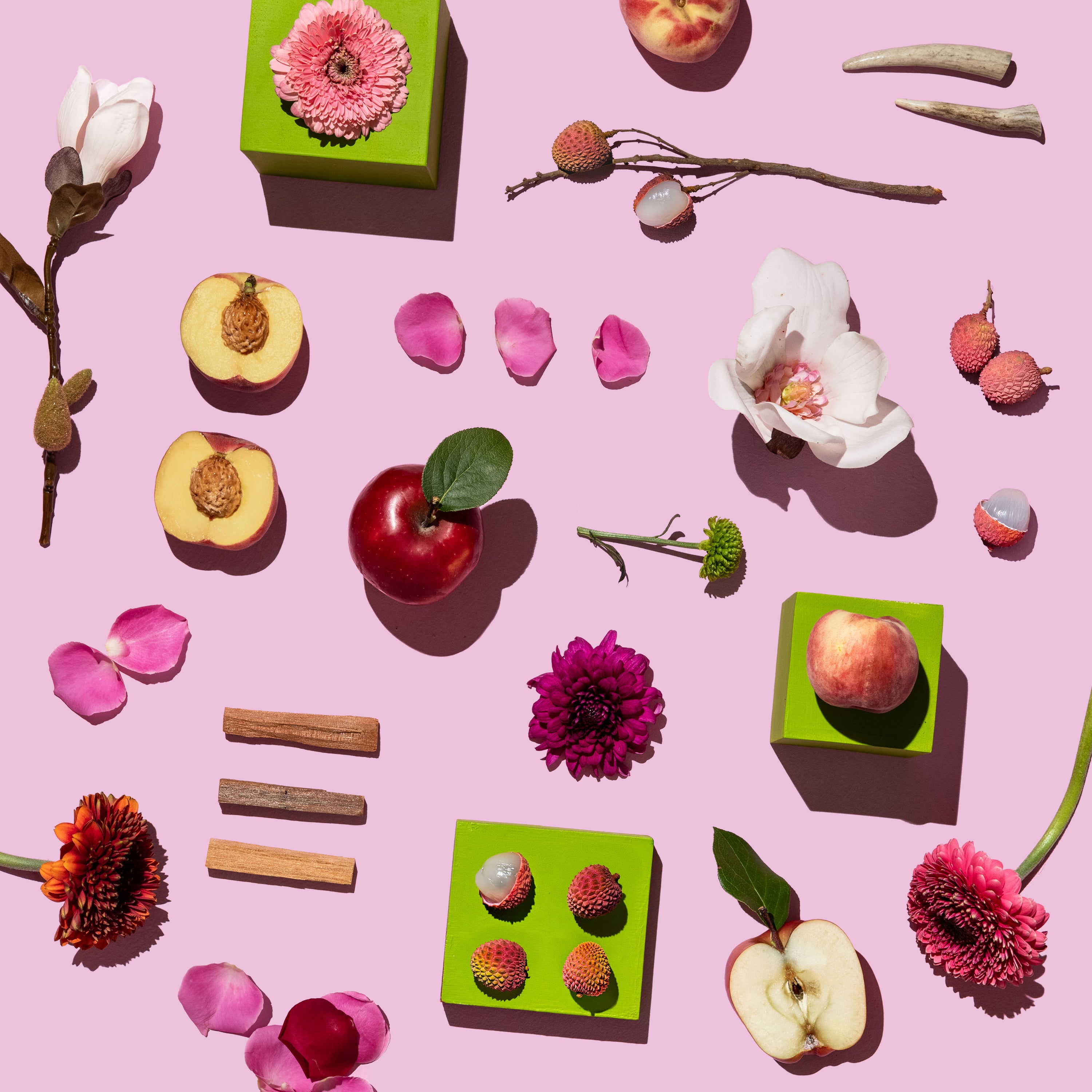 Colorful arrangement of fruits, flowers, and candies on a pink background