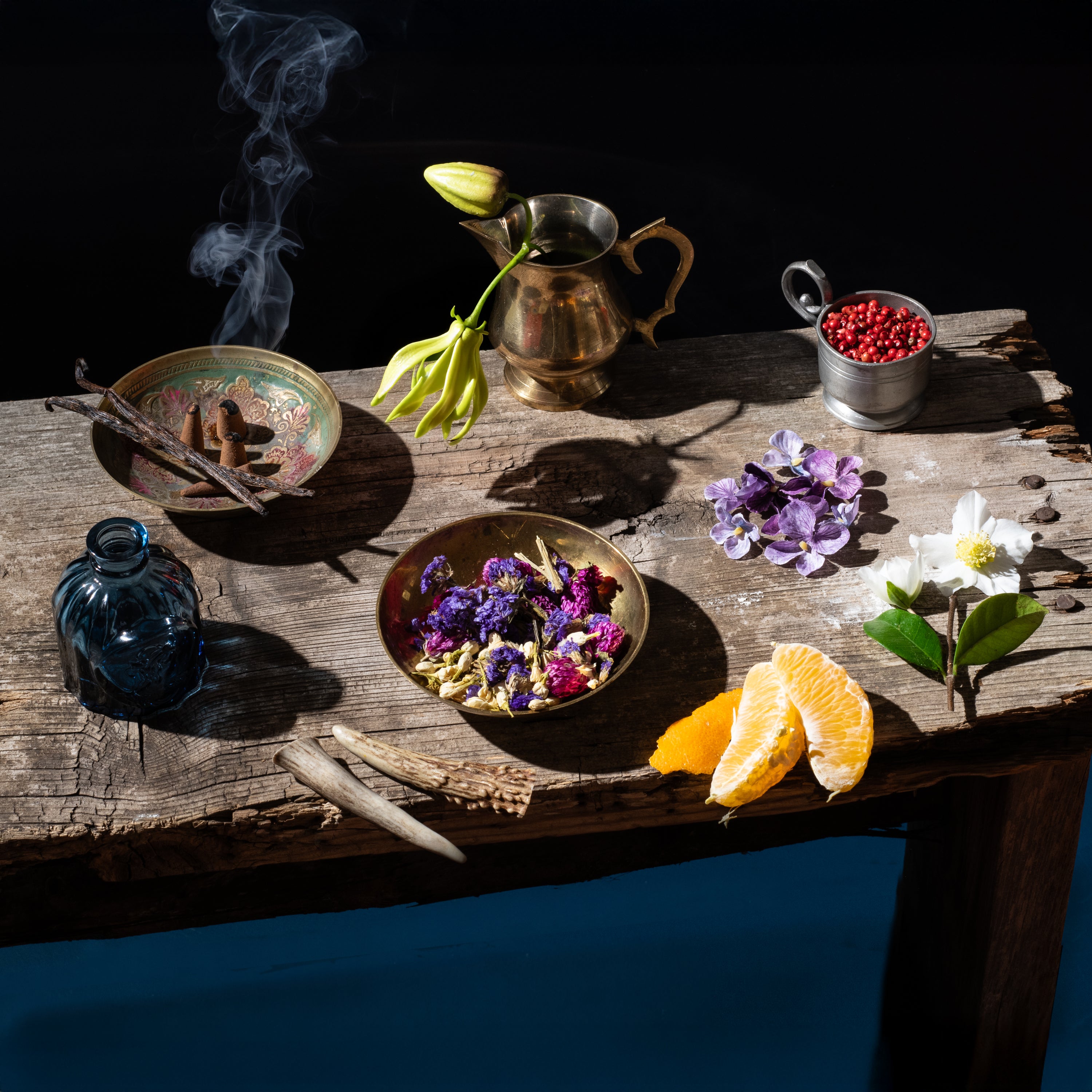 Vintage pitcher, flowers, and fruits on a rustic wooden table with a dark background