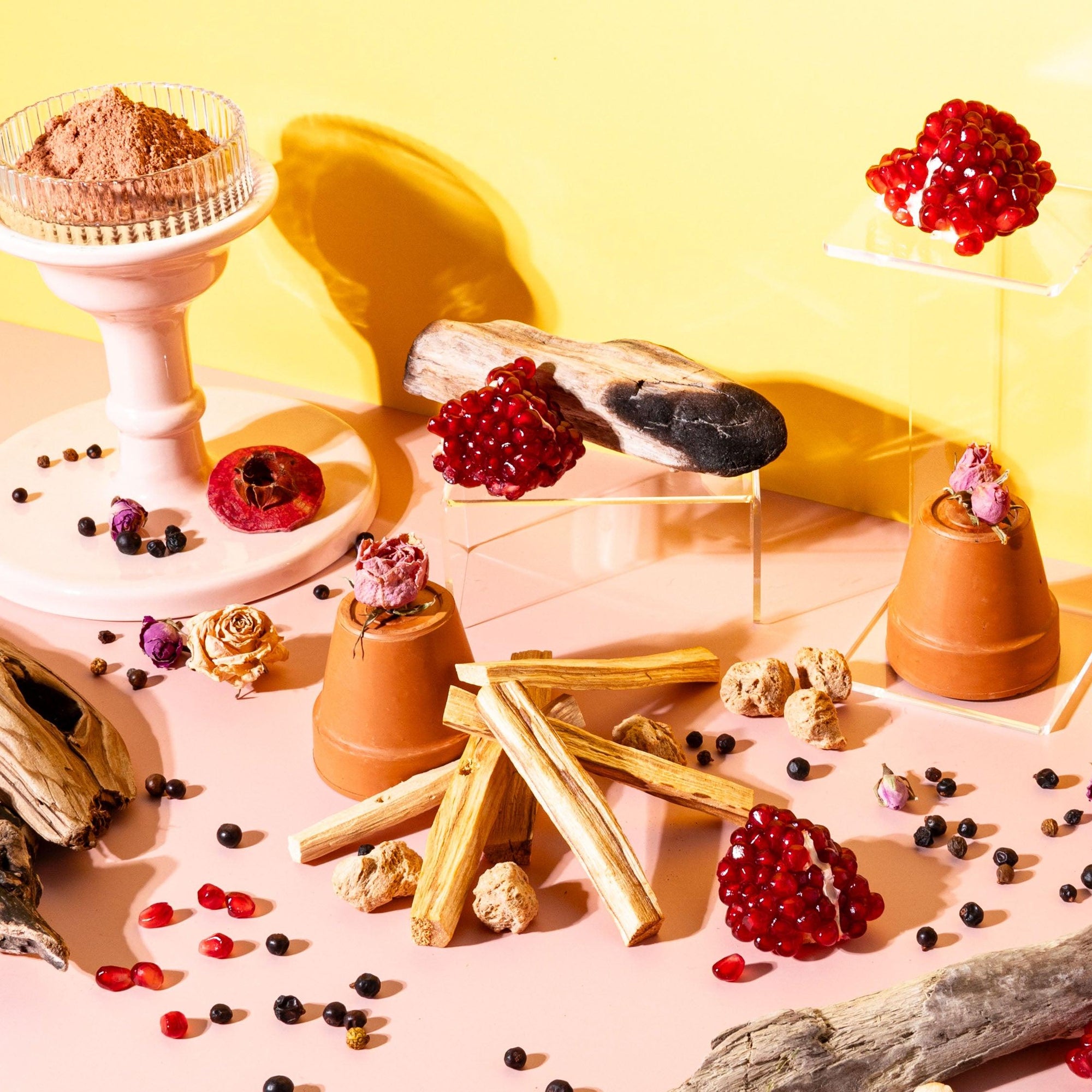 An assortment of objects related to fragrance oil display, including vases, stones, and decorative items arranged against a yellow background.