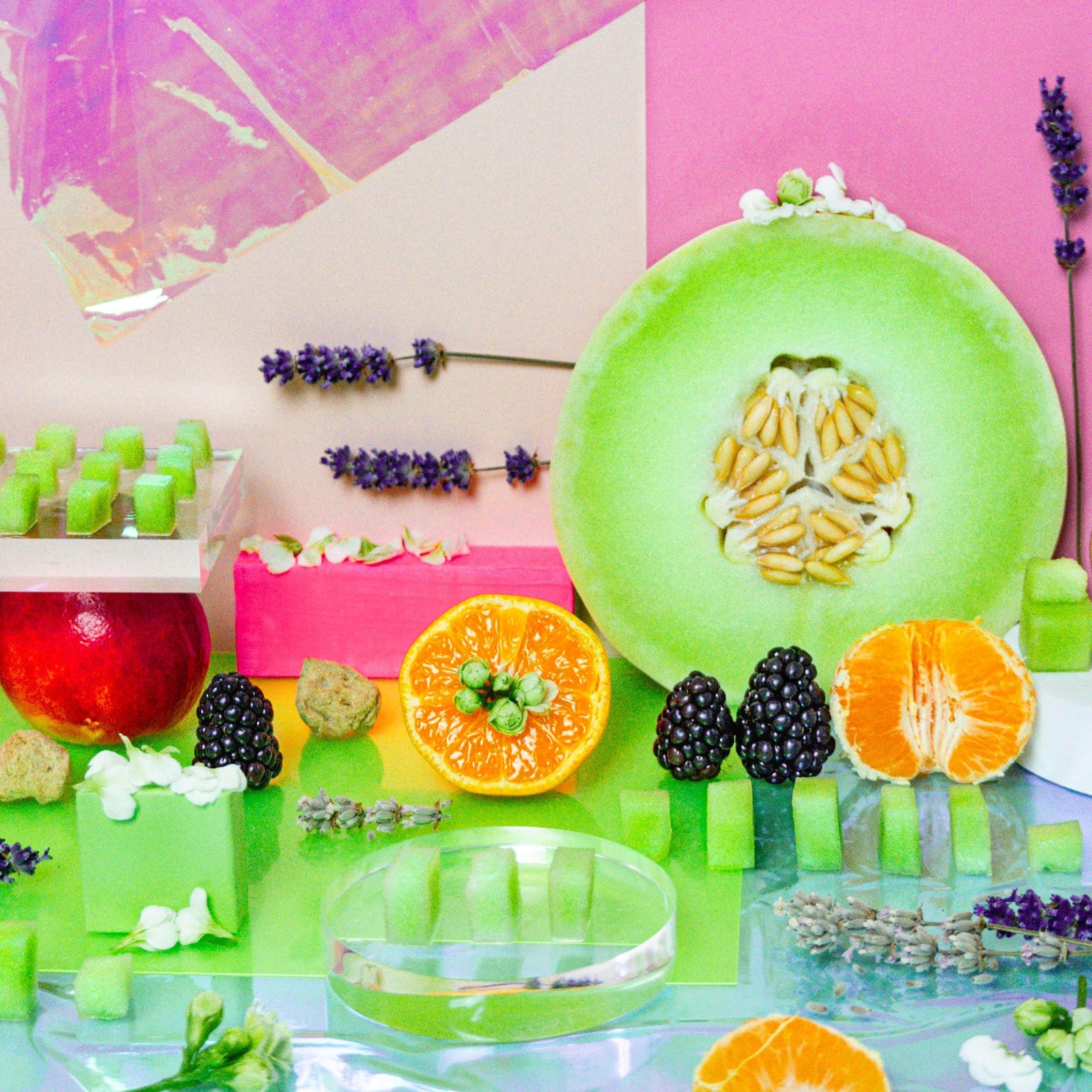Colorful dessert display with fruits and pastries on a pink and white abstract background