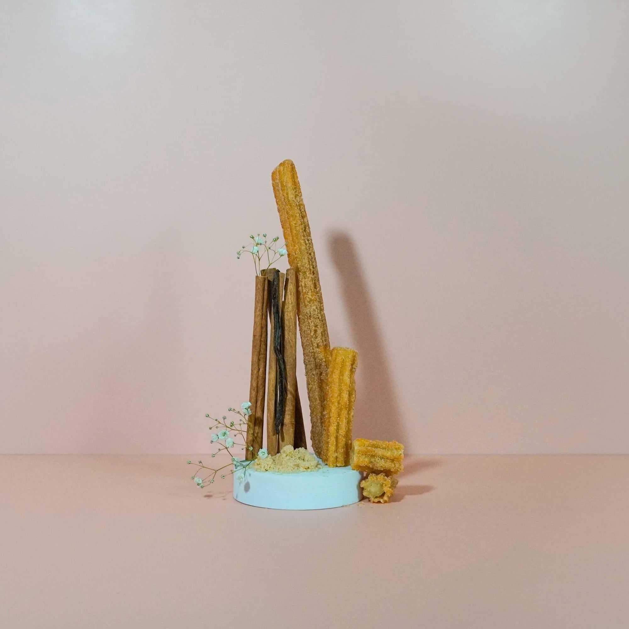 A fragrance oil bottle with a decorative display that includes cinnamon sticks and sugar crystals, suggesting a warm, pastry-like aroma.