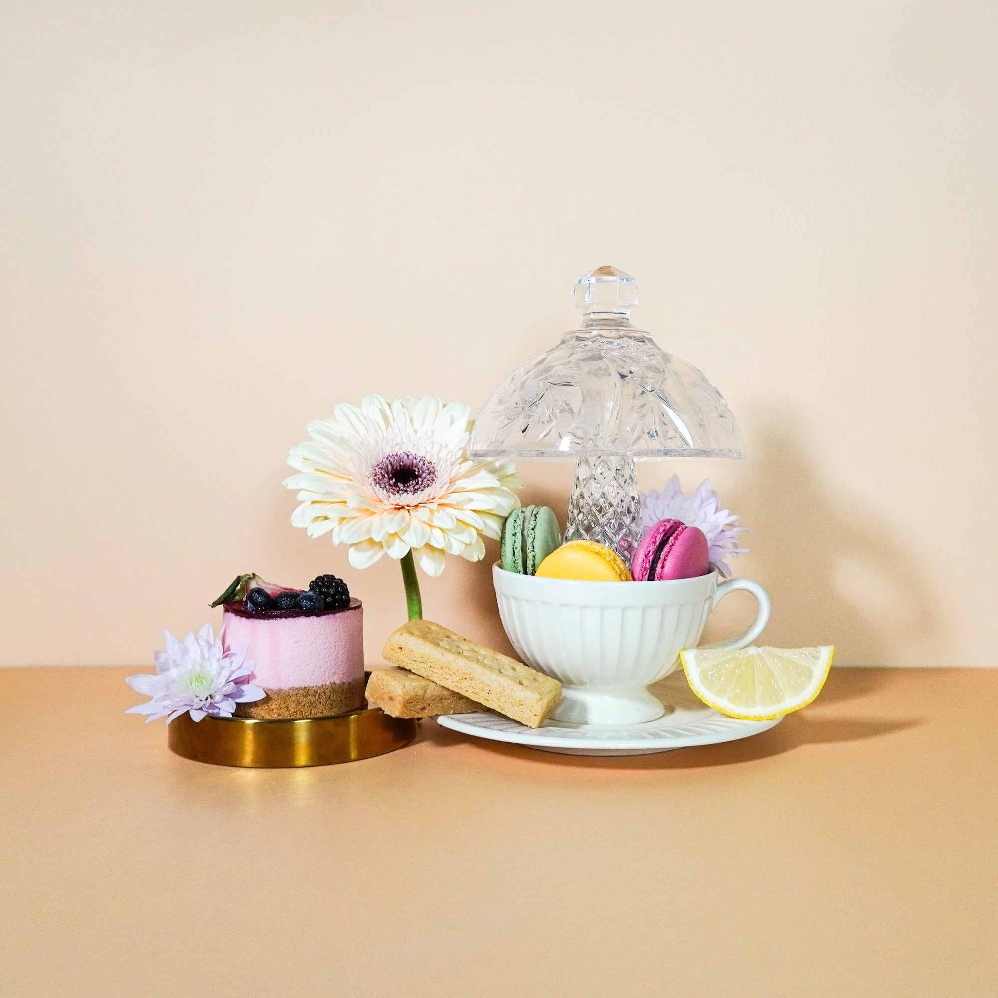 A set table with a cup of tea, biscuits, a slice of lemon, and a flower arrangement, depicting a scene of someone enjoying a tea break.